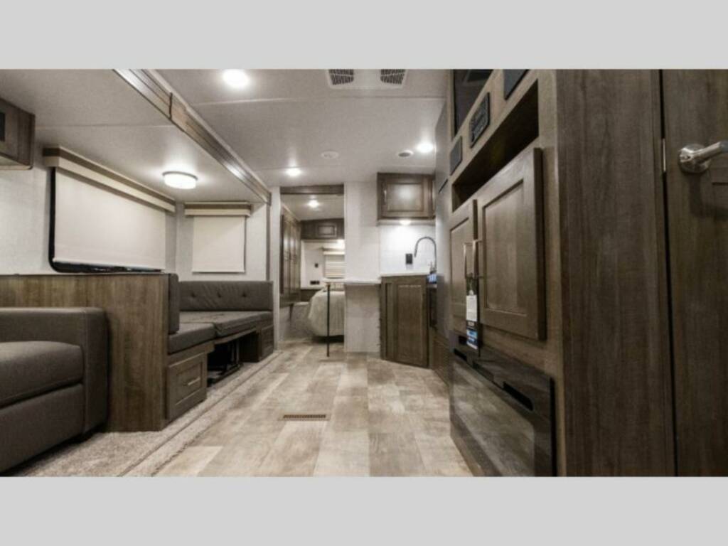 Interior view of the RV with a dinette, living space, bedroom and a kitchen.