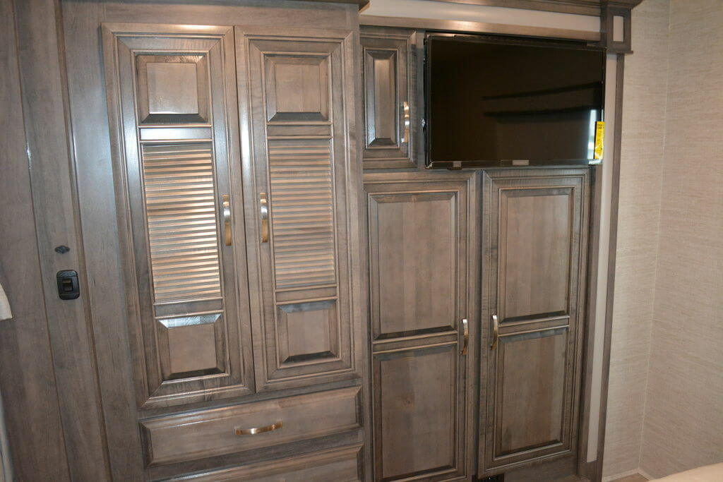 Built-in wardrobe with wooden doors and a wall-mounted TV.