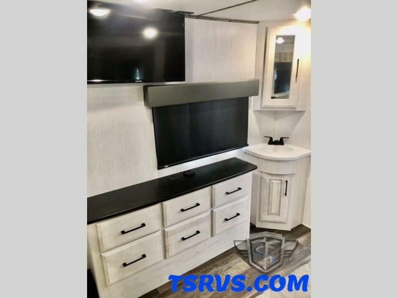 Bedroom with a dresser, sink and a TV.