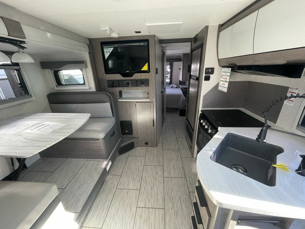 Interior view of the RV with a dinette, living space and a bedroom.