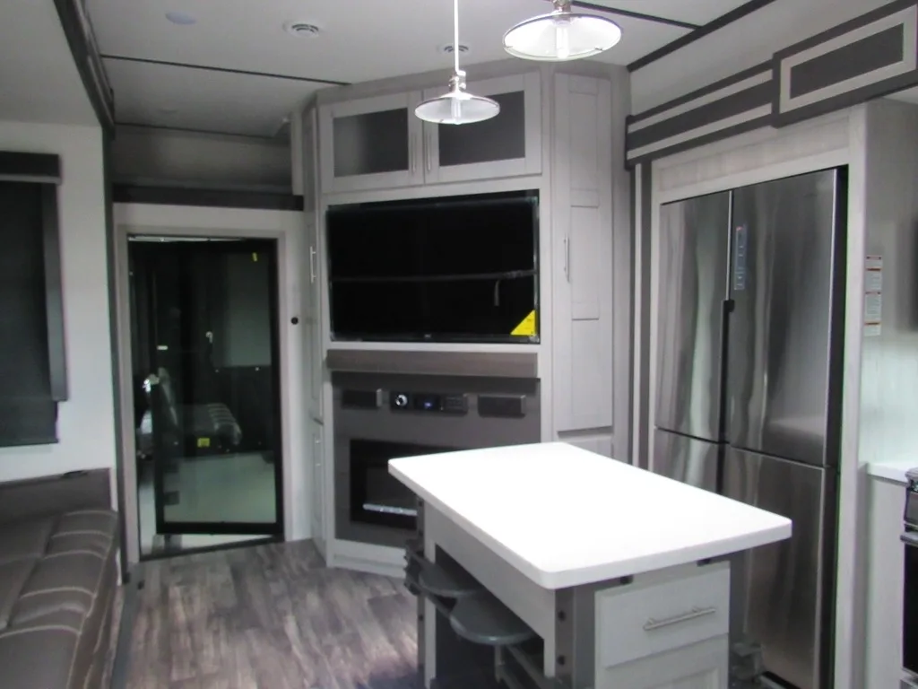 Interior view of the RV with a dinette, entertainment center, living space and a kitchen.