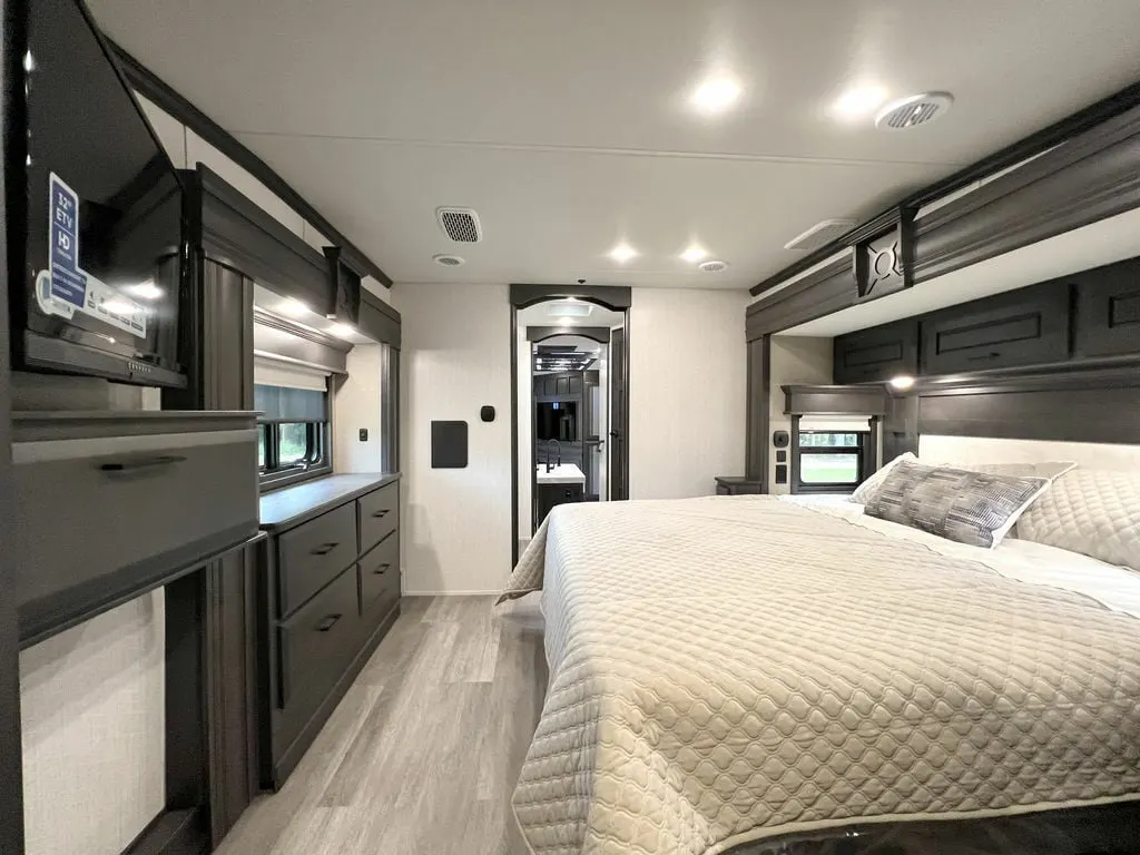 Bedroom with a king size bed, dresser, TV and cabinets.