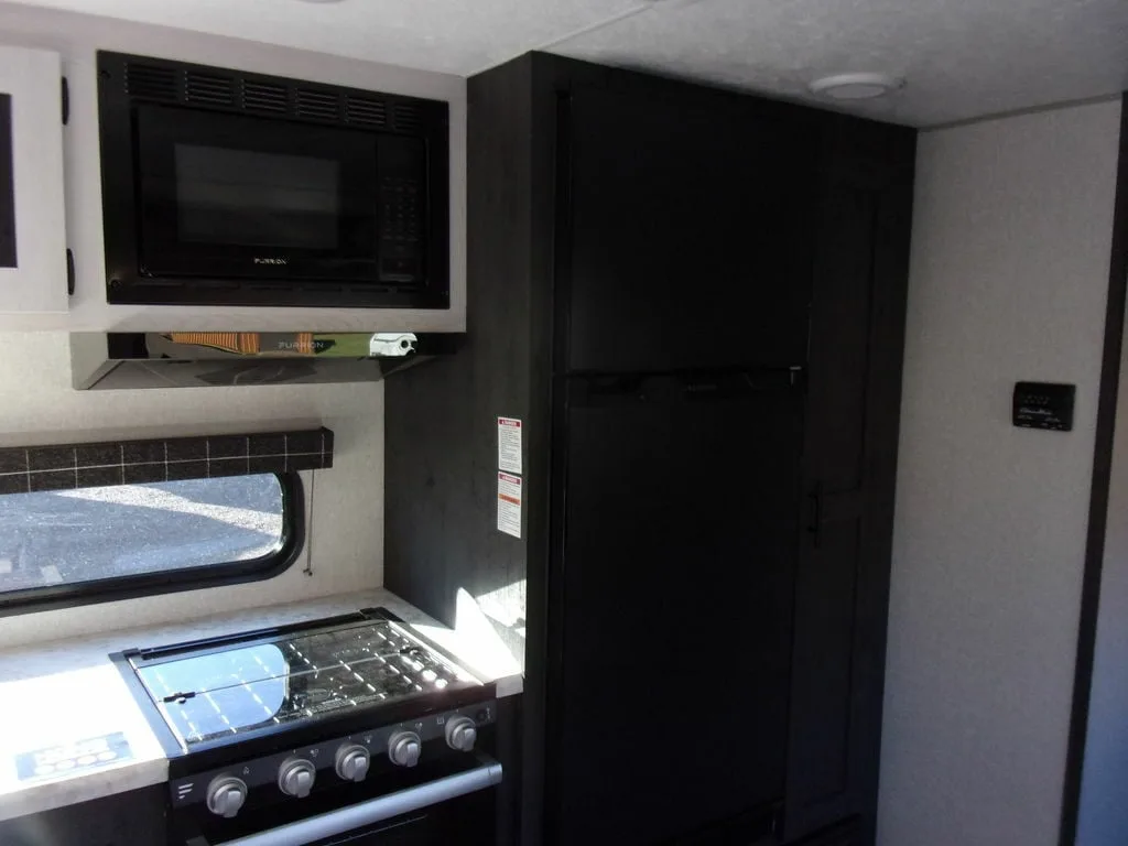 Kitchen with a gas burner, oven and a fridge.