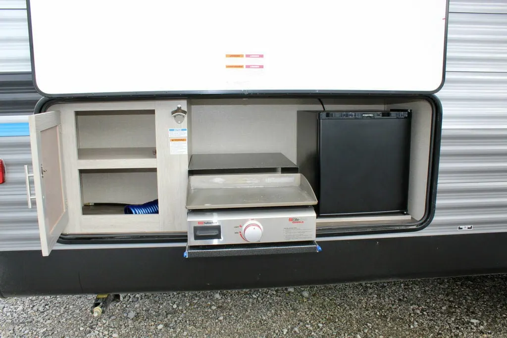 Outdoor kitchen with a pull out griddle, cabinet and a fridge.