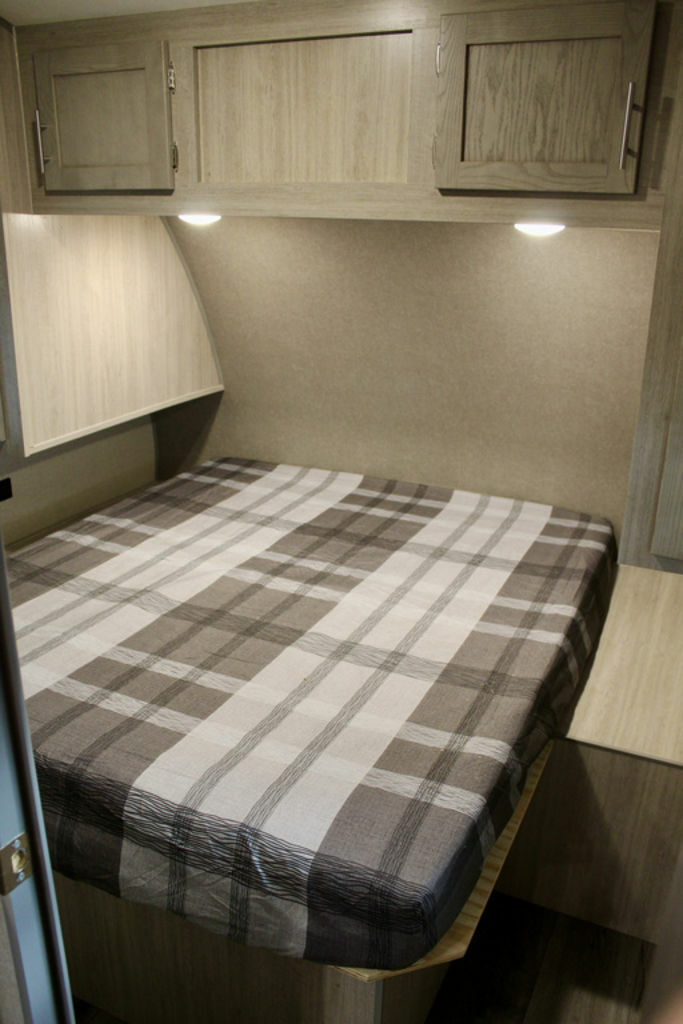 Bedroom with a queen size bed, overhead cabinets and shirt closets.