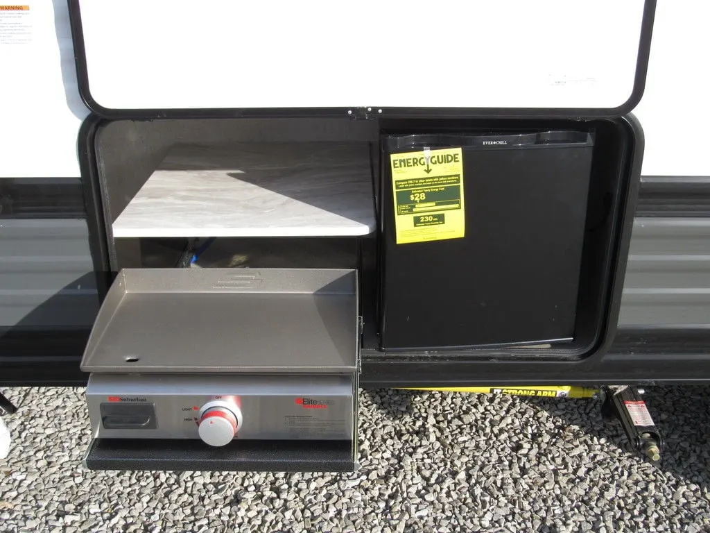 Outdoor kitchen with a gas griddle and a fridge.