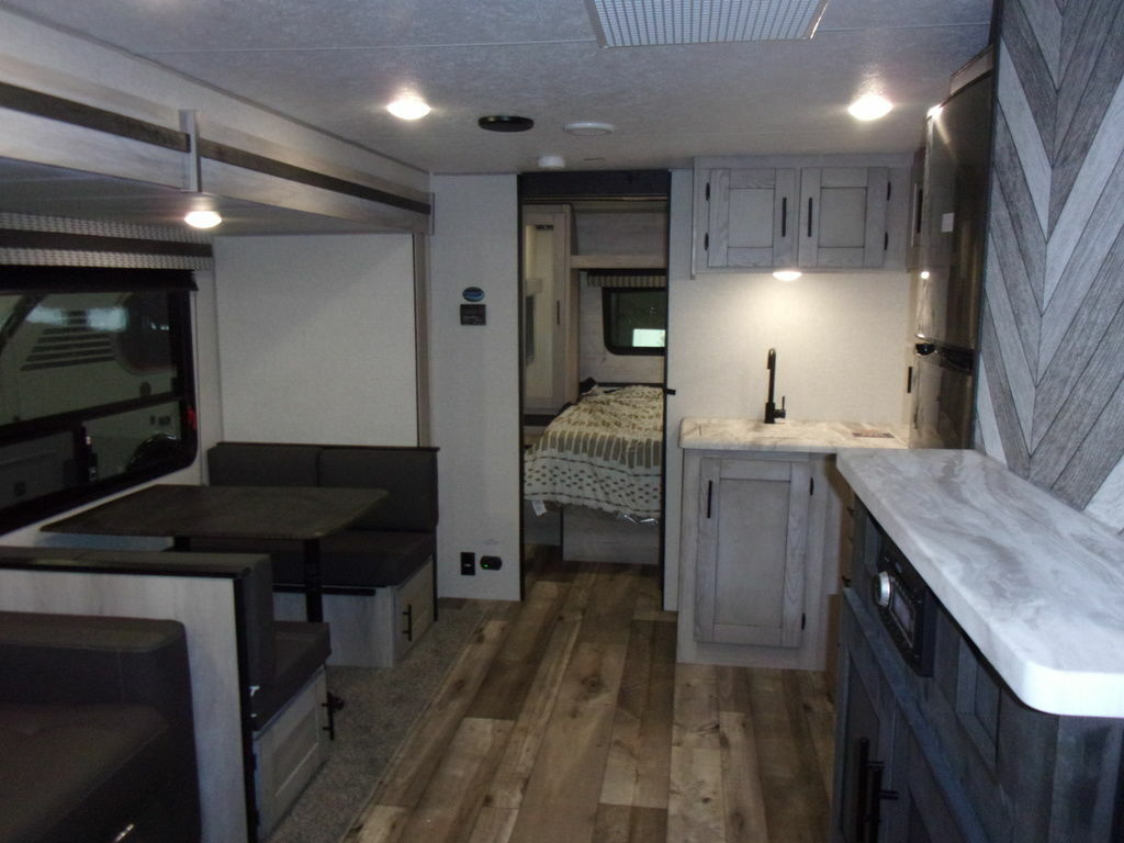 Interior view of the RV with a dinette, bedroom and a kitchen.