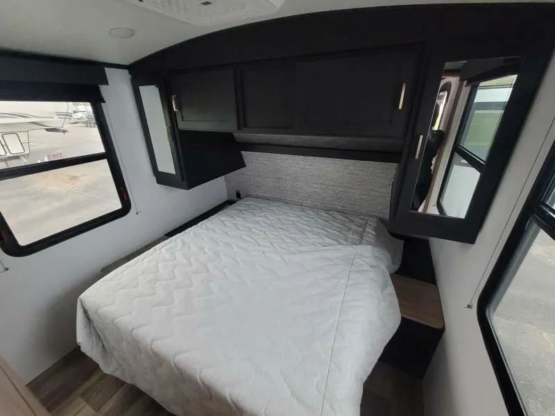 Bedroom with a queen size bed, overhead cabinets and shirt closets.