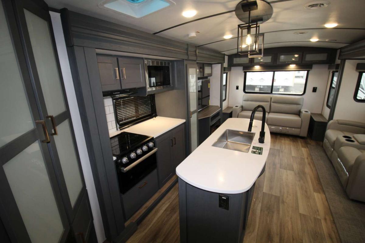 Interior view of the RV with an entertainment center, living space and a kitchen.