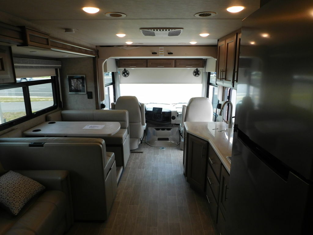 Interior view of the RV with a dinette, living space, kitchen and the driver's seat.