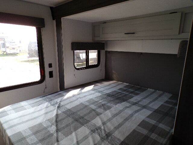 Bedroom with a queen size bed and overhead cabinets.