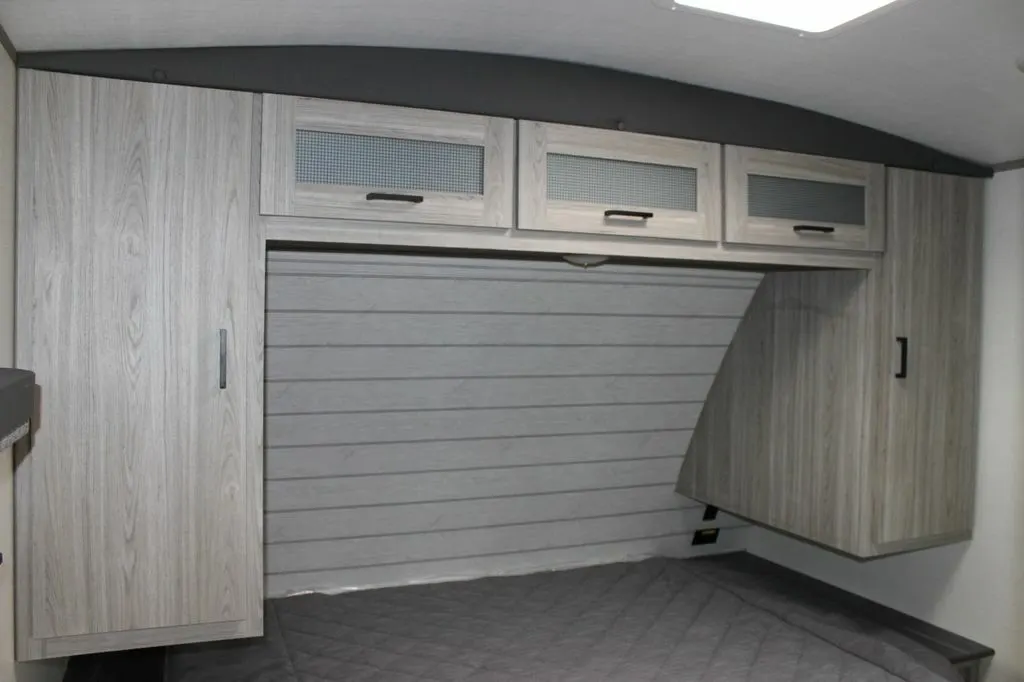 Bedroom with a queen size bed, overhead cabinets and shirt closets.