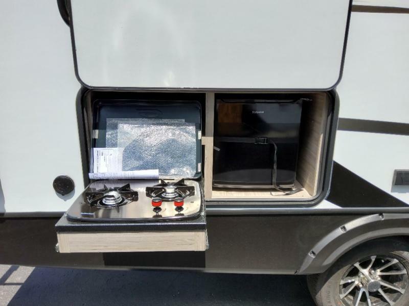 Outdoor kitchen with a gas burner and a fridge.