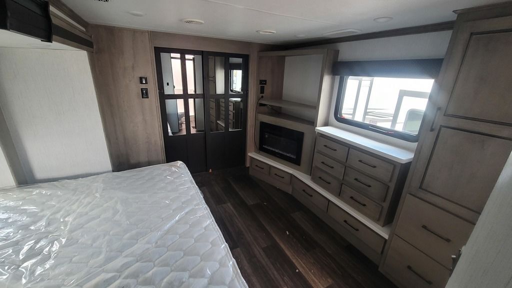 Bedroom with a king size bed, fireplace, drawers and a closet.