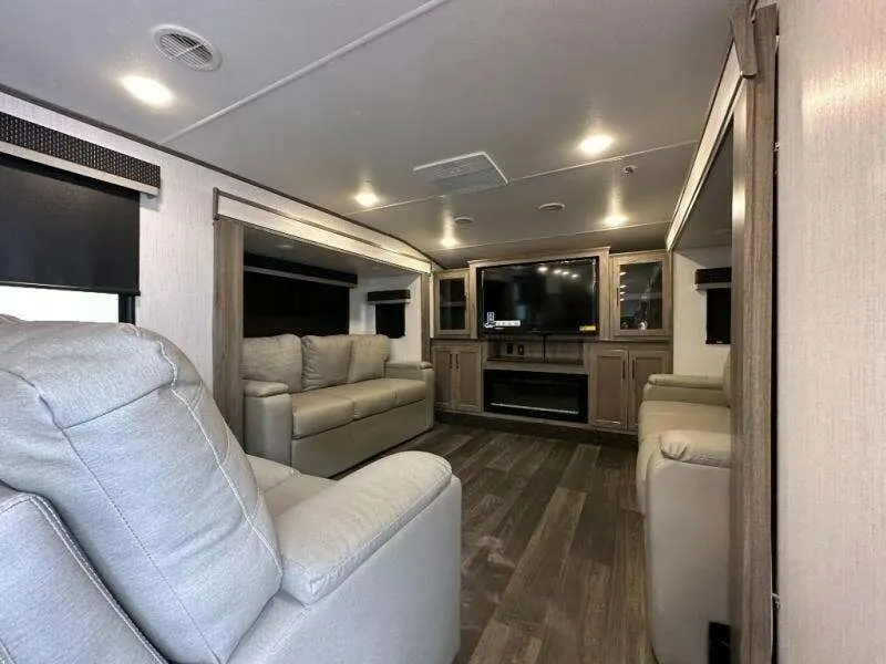 Living space with leather seats, a TV and a fireplace.