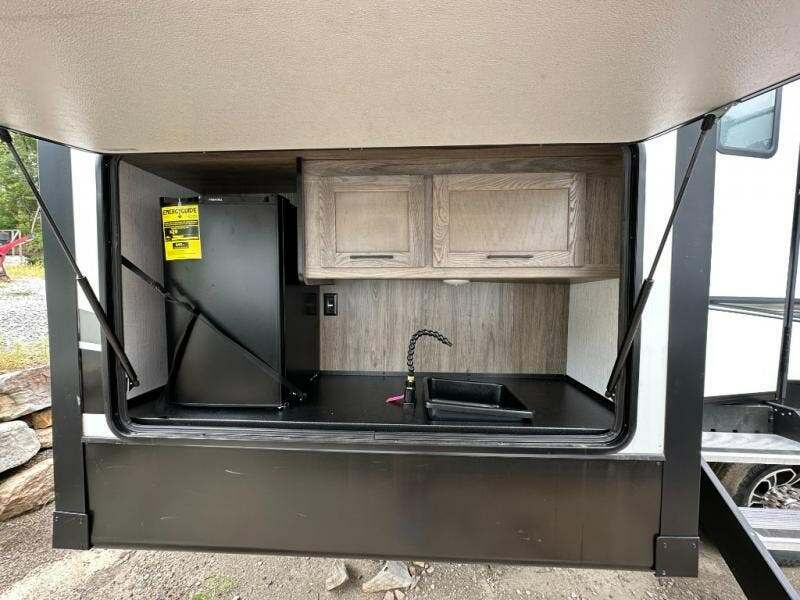 Outdoor kitchen with a fridge and a sink.