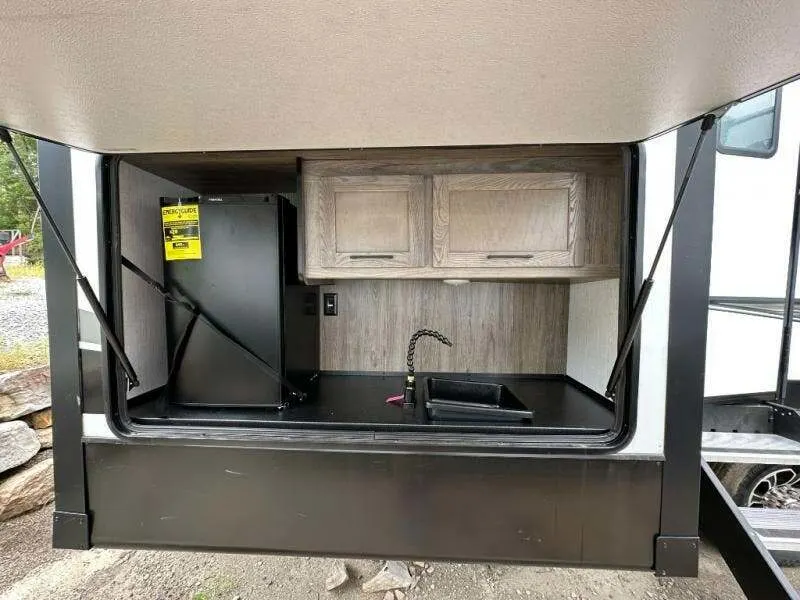 Outdoor kitchen with a fridge and a sink.