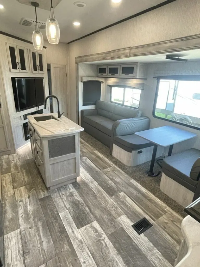 Interior view of the RV with a dinette, living space and entertainment center.