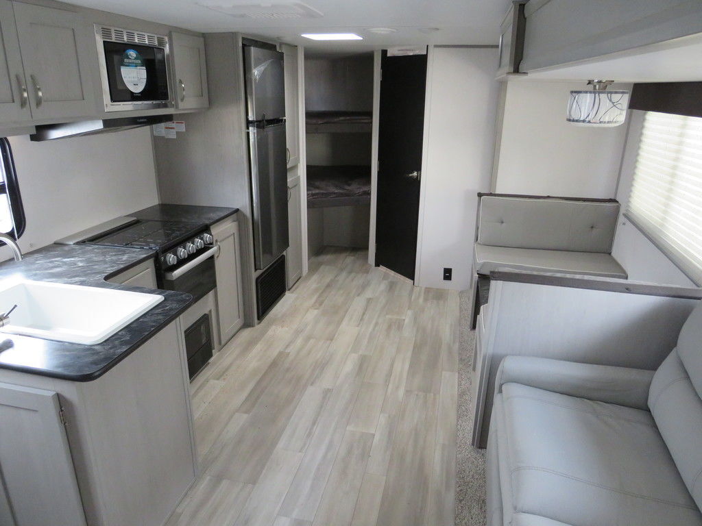 Interior view of the RV with a dinette, living space, bedroom and a kitchen.