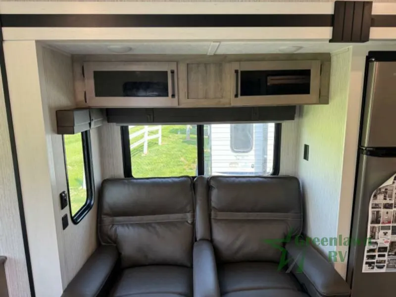 Living space with theater seats and overhead cabinets.