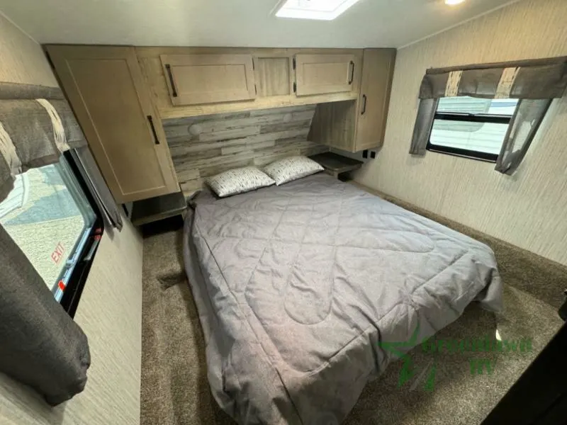 Bedroom with a queen size bed, overhead cabinets and shirt closets.