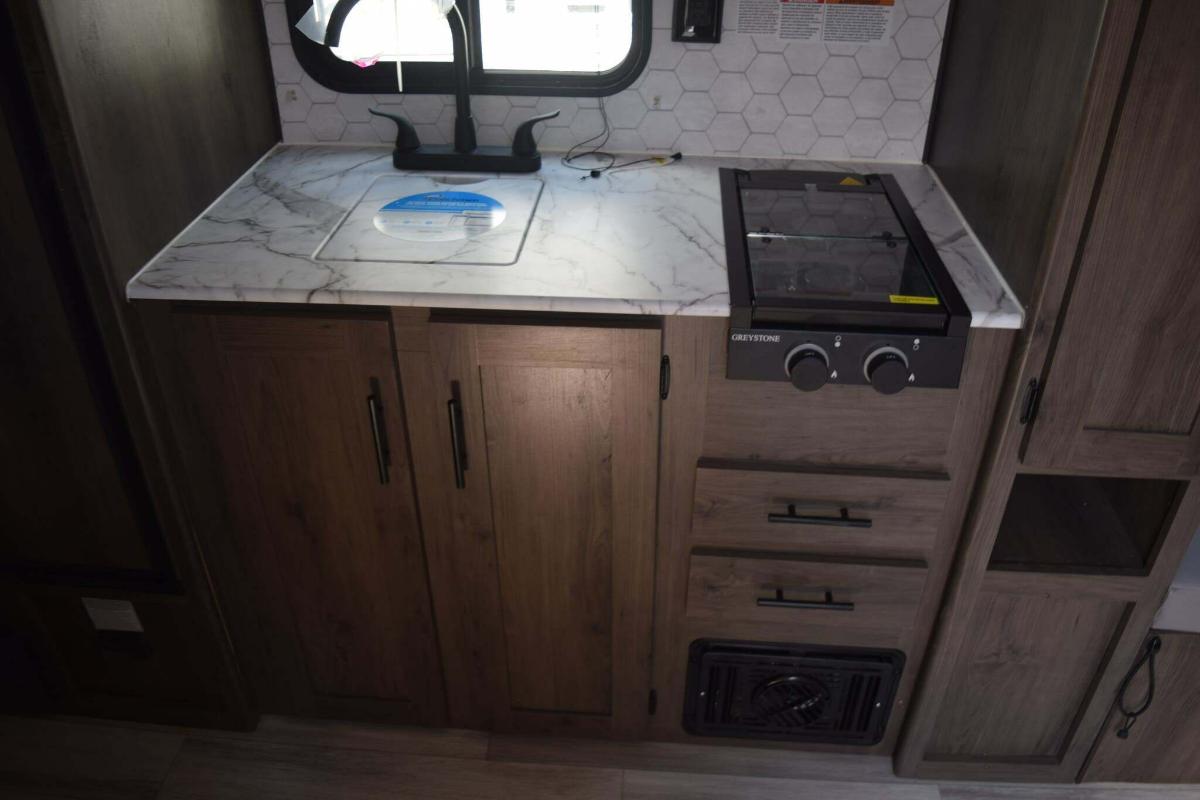 Kitchen with a gas burner, sink and cabinets.