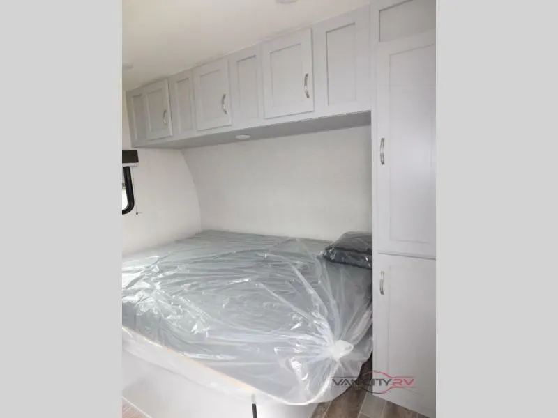 Bedroom with a queen size bed, overhead cabinets and a shirt closet.