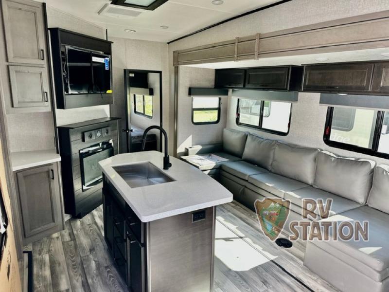 Interior view of the RV with an entertainment center, living space and a kitchen.