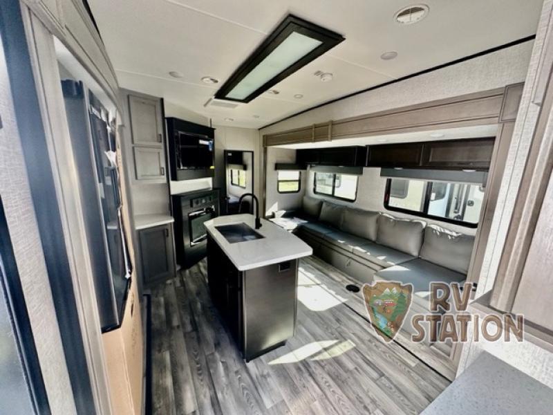 Interior view of the RV with an entertainment center, living space and a kitchen.