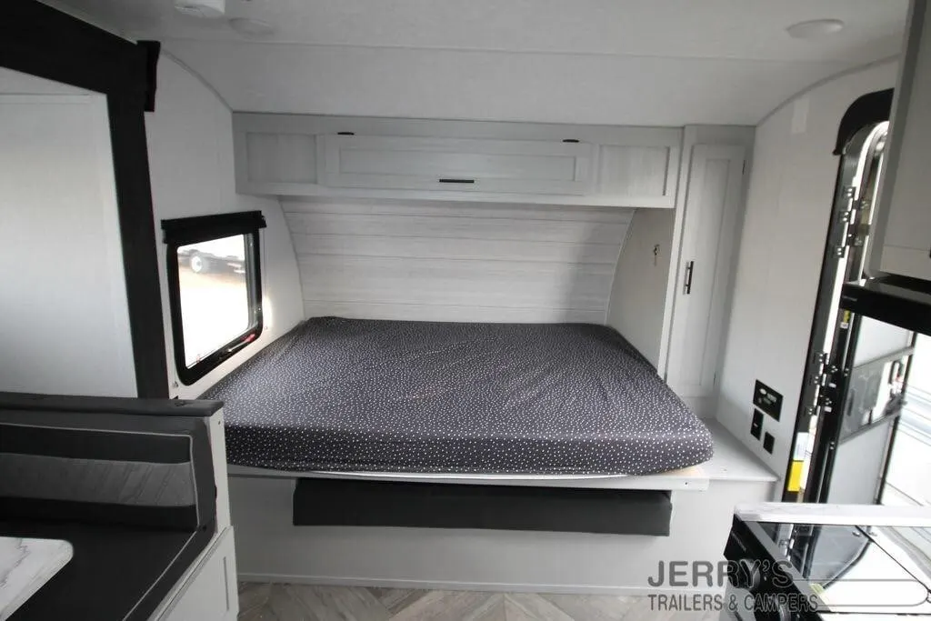 Bedroom with a queen size bed, overhead cabinets and a shirt closet.