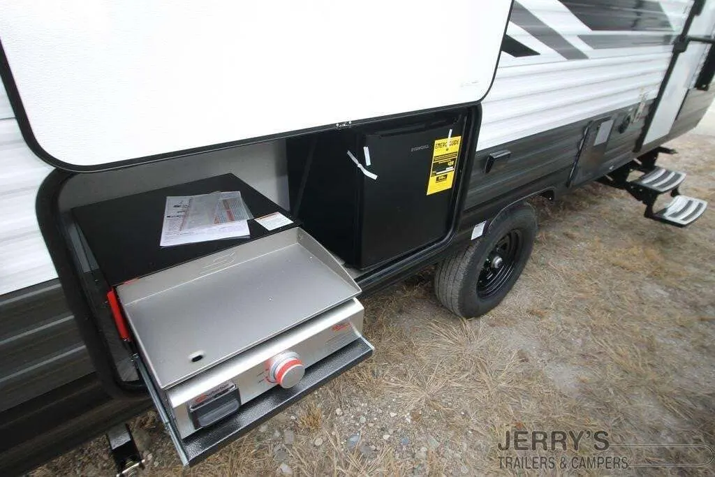 Outdoor kitchen with a gas griddle and a fridge.