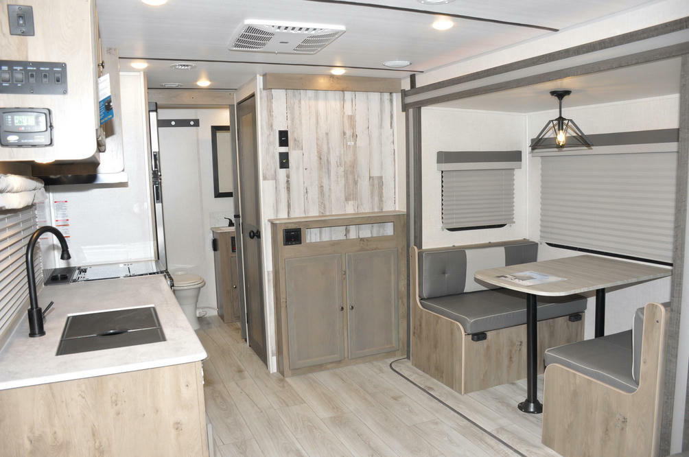 Interior view of the RV with a dinette, bathroom and a kitchen.