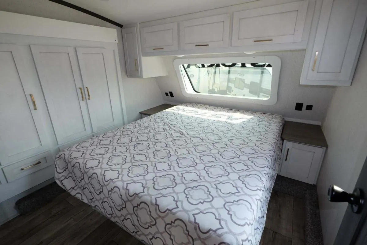 Bedroom with a queen size bed, overhead cabinets and shirt closets.