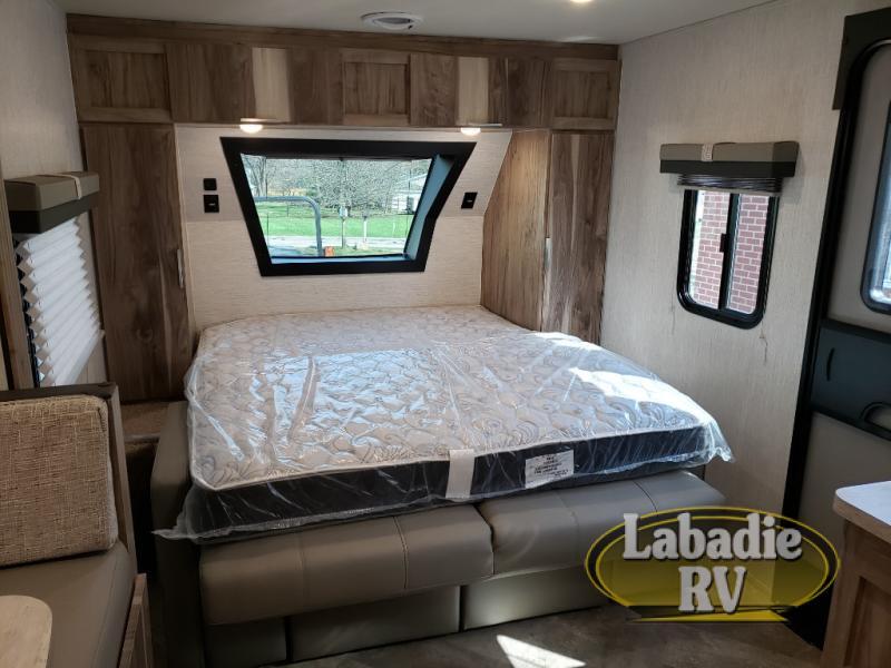 Bedroom with a queen size bed, overhead cabinets and shirt closets.