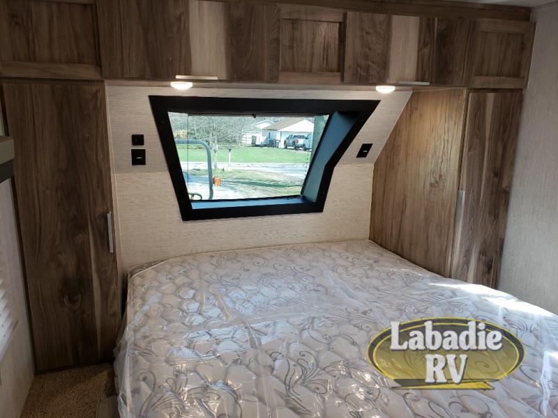 Bedroom with a queen size bed, overhead cabinets and shirt closets.