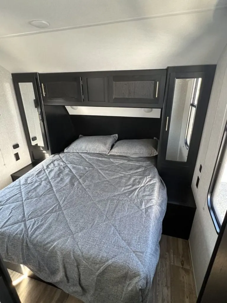 Bedroom with a queen size bed, overhead cabinets and shirt closets.