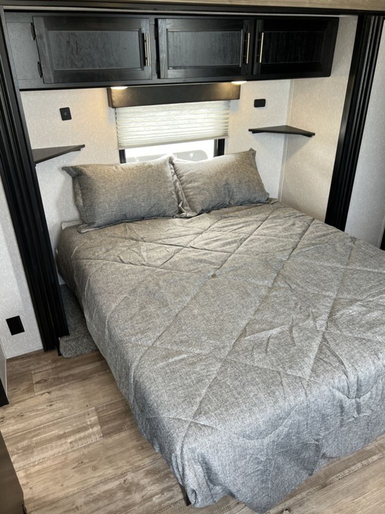 Bedroom with a queen size bed and overhead cabinets.