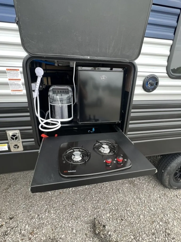 Outdoor kitchen with a gas burner and a fridge.