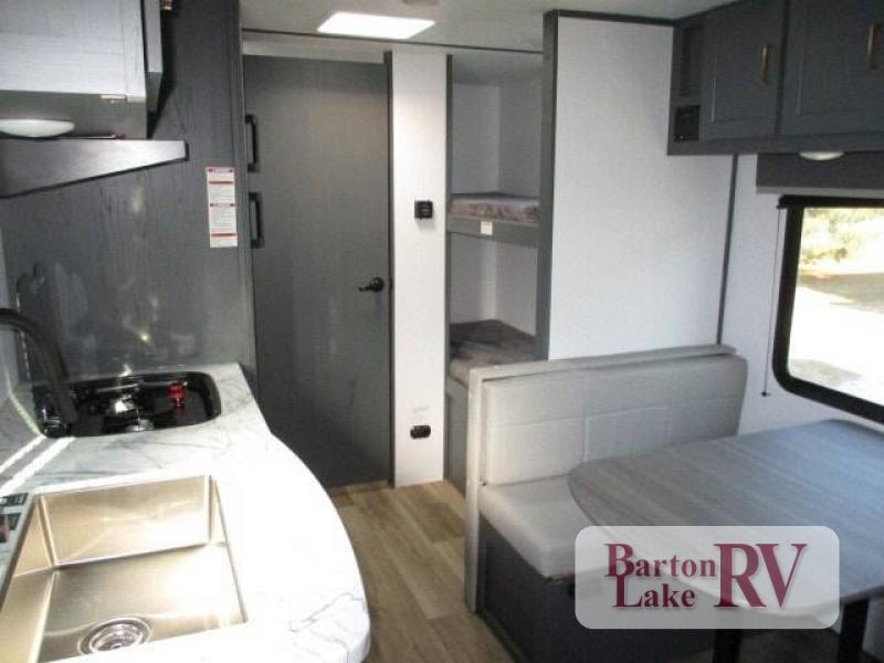 Interior view of the RV with a dinette, bedroom and a kitchen.