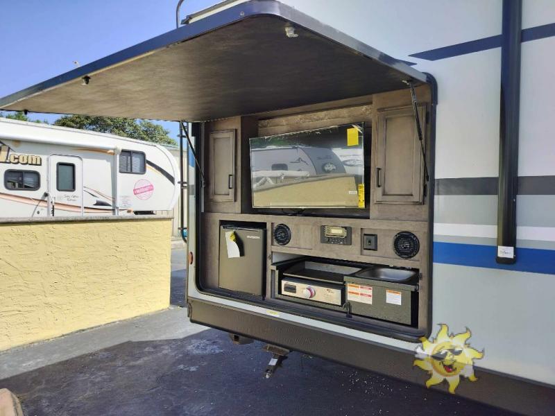 Outdoor kitchen with a gas griddle, TV and a fridge.