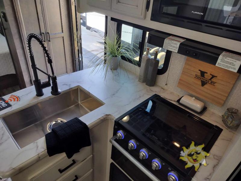 Kitchen with a gas range, oven, sink and drawers.