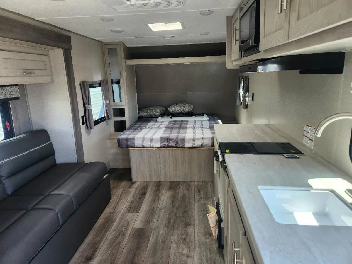 Interior view of the RV with a bedroom, living space and a kitchen.