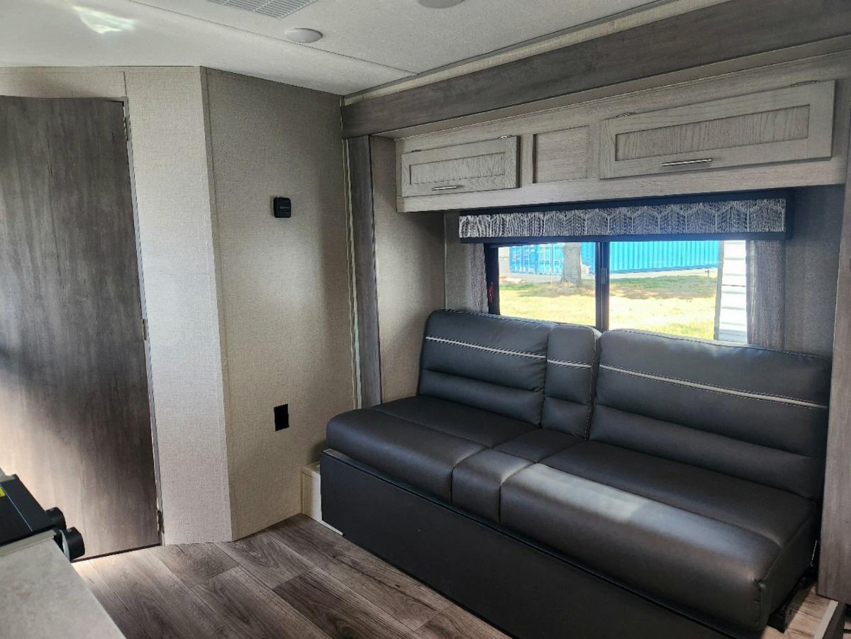 Living space with leather seats and overhead cabinets.  