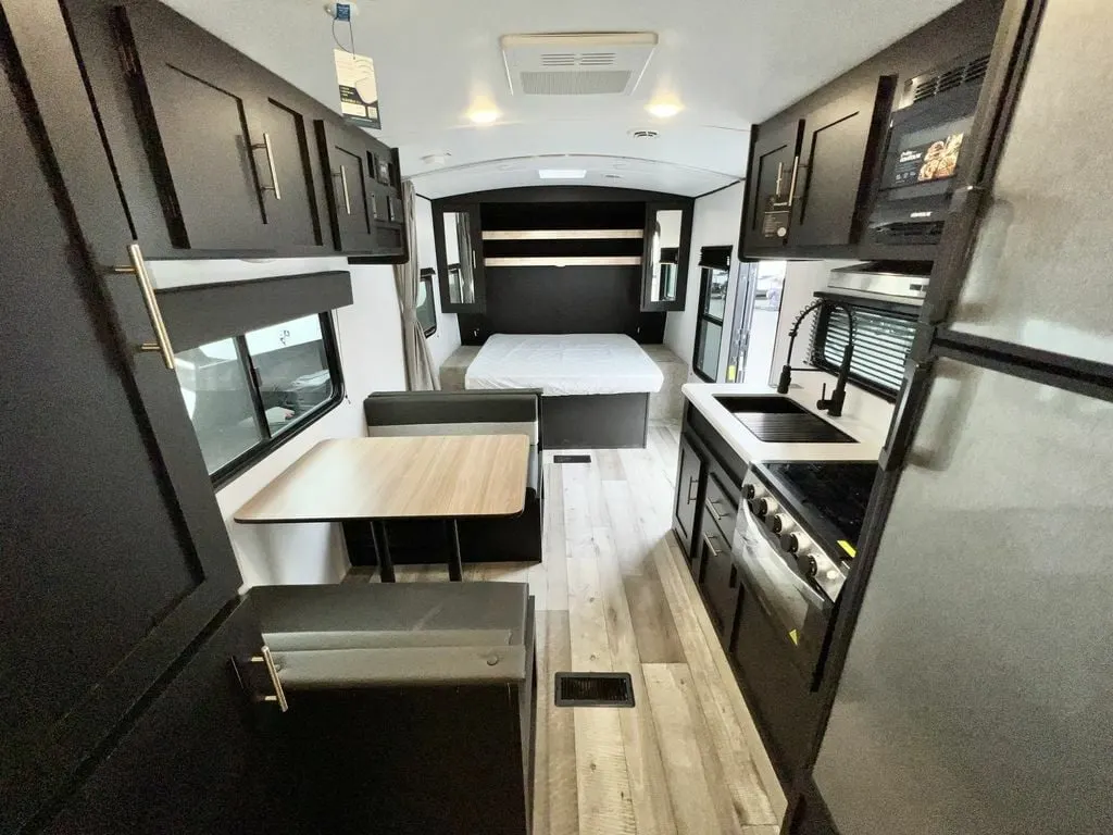 Interior view of the RV with a dinette, bedroom and a kitchen.