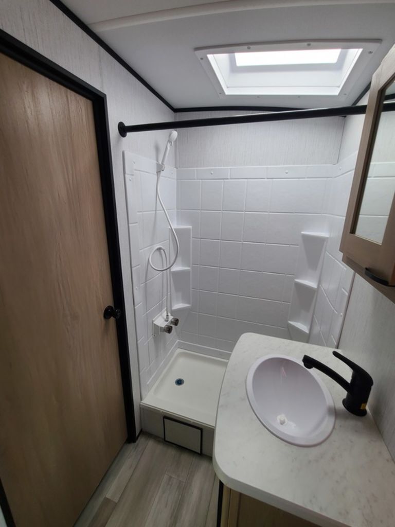 Bathroom with a sink, skylight and a shower.