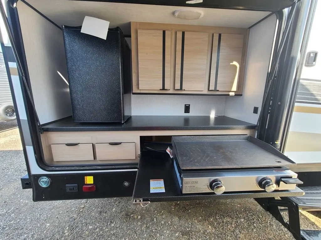 Outdoor kitchen with a gas burner and fridge.