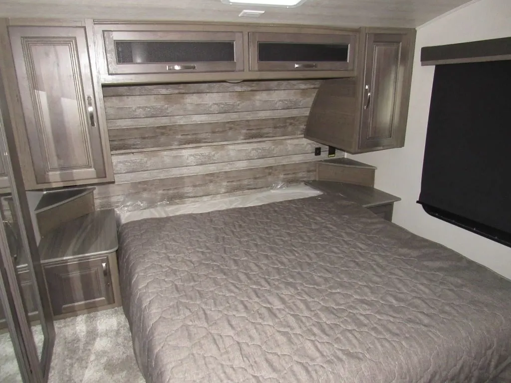 Bedroom with a queen size bed, overhead cabinets and shirt closets.