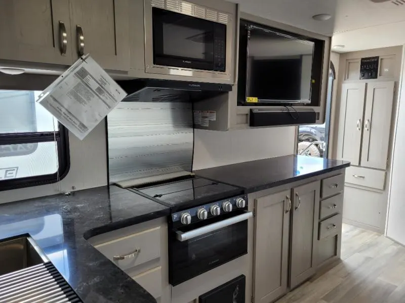 Kitchen with a gas range, oven, TV and cabinets.