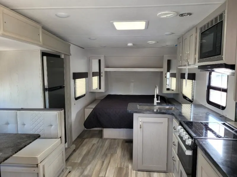 Interior view of the RV with a dinette, bedroom and a kitchen.