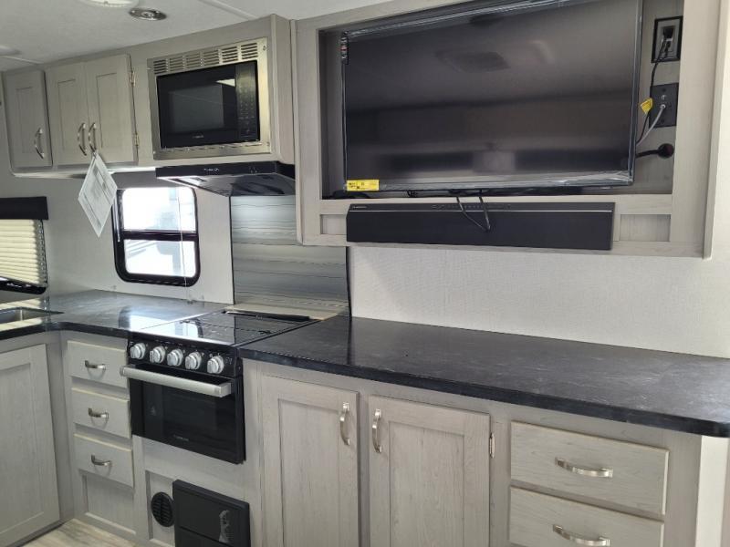 Kitchen with a gas range, oven, TV and cabinets.